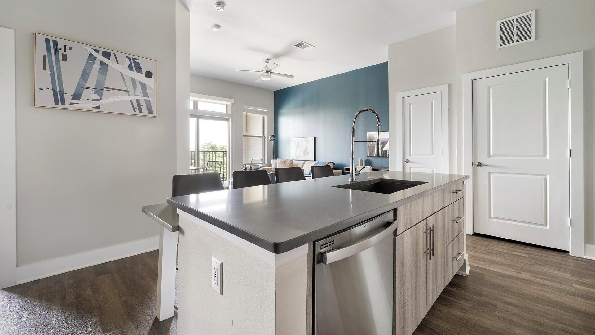 Una cocina moderna con una isla central, lavavajillas integrado y una zona de comedor con sillas.