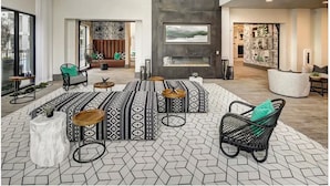 A spacious lobby with a high ceiling, patterned floor tiles, and a central seating area with a fireplace. - Landing | Stunning 1BD, Pool, Courtyard (Austin)