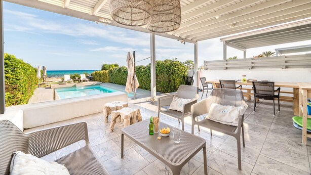 Un espace extérieur abrité comprenant une piscine, des chaises longues et une table avec des boissons.