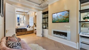 A spacious living room with a fireplace, a large TV mounted on the wall, and a cozy seating area with a pink sofa and a fluffy rug. - Apartment in Marylebone with Jacuzzi Bath (London)