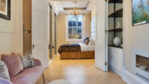 A spacious room with a large bed, a sofa, a fireplace, and a chandelier. - Apartment in Marylebone with Jacuzzi Bath (London)