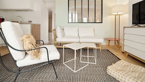A modern living room with a white sofa, a white armchair, a small white table, a floor lamp, and a TV mounted on the wall. - Magnificent apartment - AC- 2BR- Saint-Tropez (Saint-Tropez)