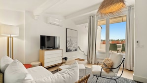A modern living room with a flat-screen TV, a sofa, a chair, and a large window offering a view of the outdoors. - Magnificent apartment - AC- 2BR- Saint-Tropez (Saint-Tropez)