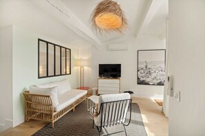 A modern, well-lit room with a sofa, a TV, and a large framed picture on the wall.