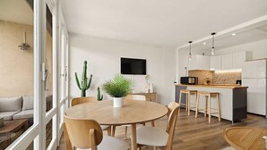 Eine moderne Küche mit Essbereich, einem Flachbildfernseher und einem großen Fenster.