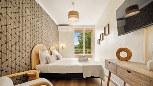 Ein modernes Schlafzimmer mit Bett, Nachttisch und Blick auf Grünfläche.