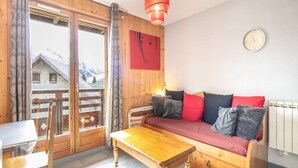A cozy room with a wooden sofa, a wooden table, and a window with a view of mountains.