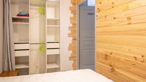 A bedroom with a bed, a wardrobe with multiple shelves, and a wooden wall.