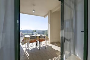 An open balcony with a table and chairs, a hanging light fixture, and a view of the landscape.