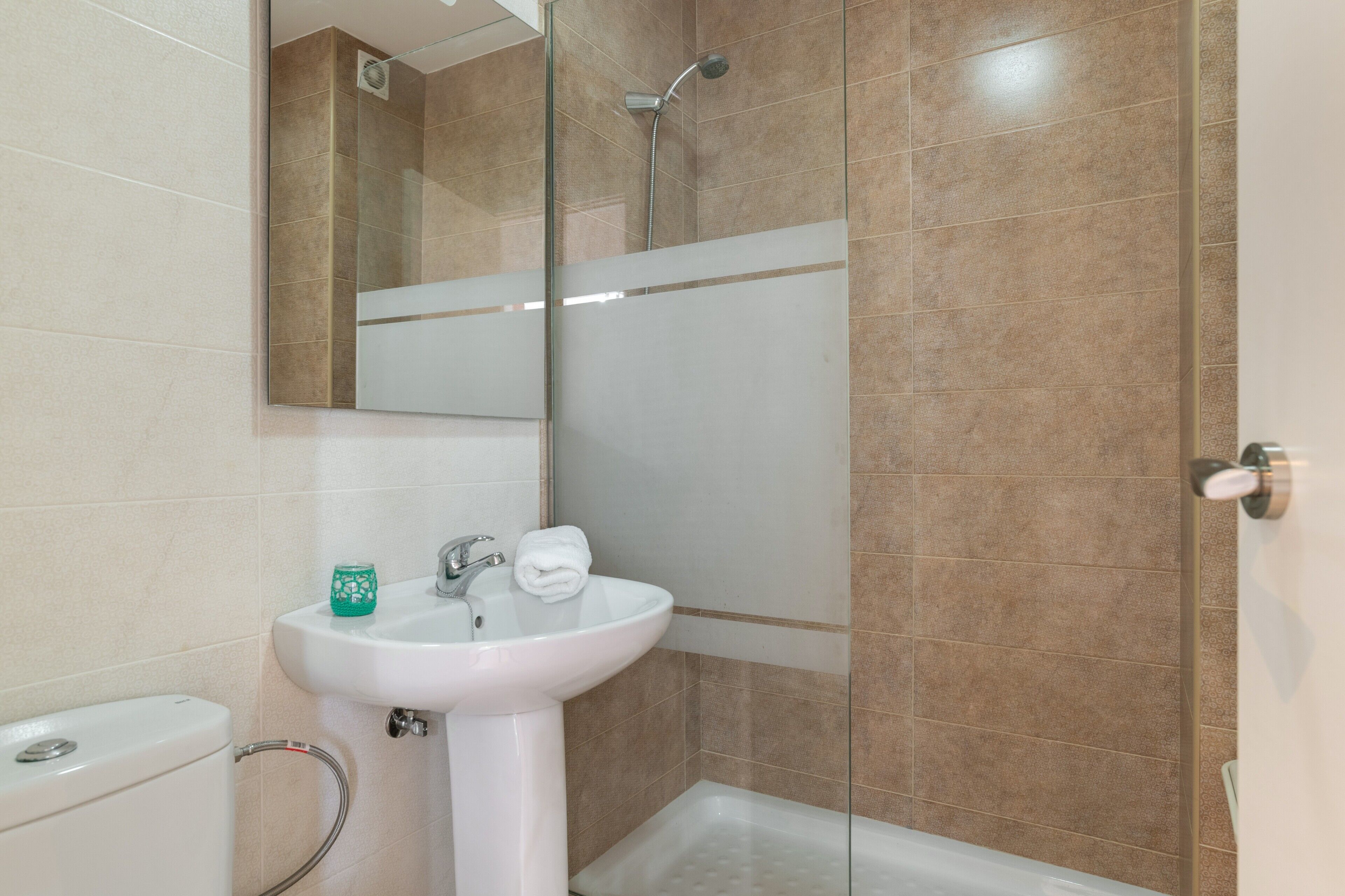 Un baño con lavamanos blanco, inodoro, ducha y espejo.