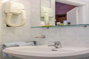 Un baño con lavamanos, toallero y espejo.