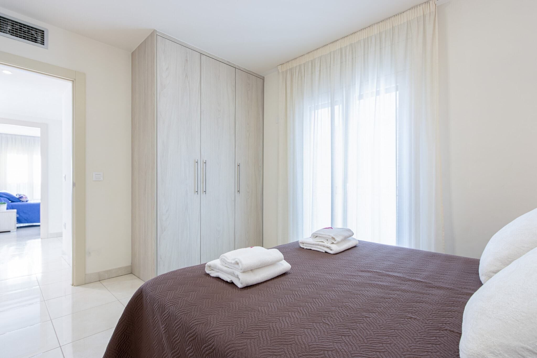 Een hotelkamer met een bed, een kledingkast en een badkamer op de achtergrond.