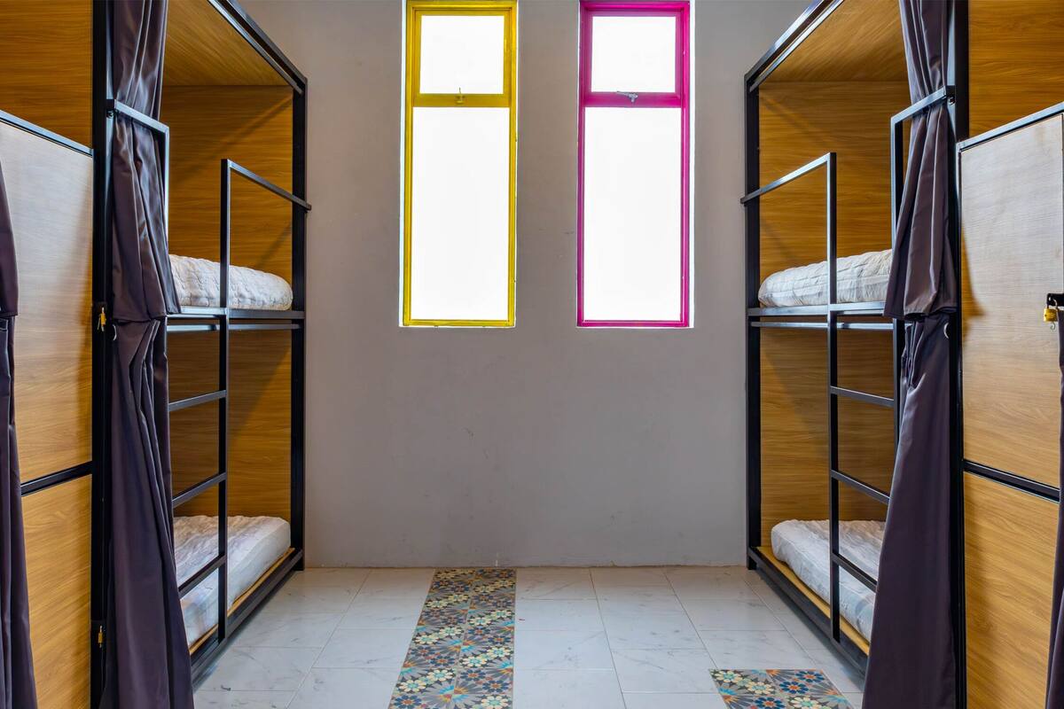 Una habitación con literas, una alfombra estampada y una pared lisa.