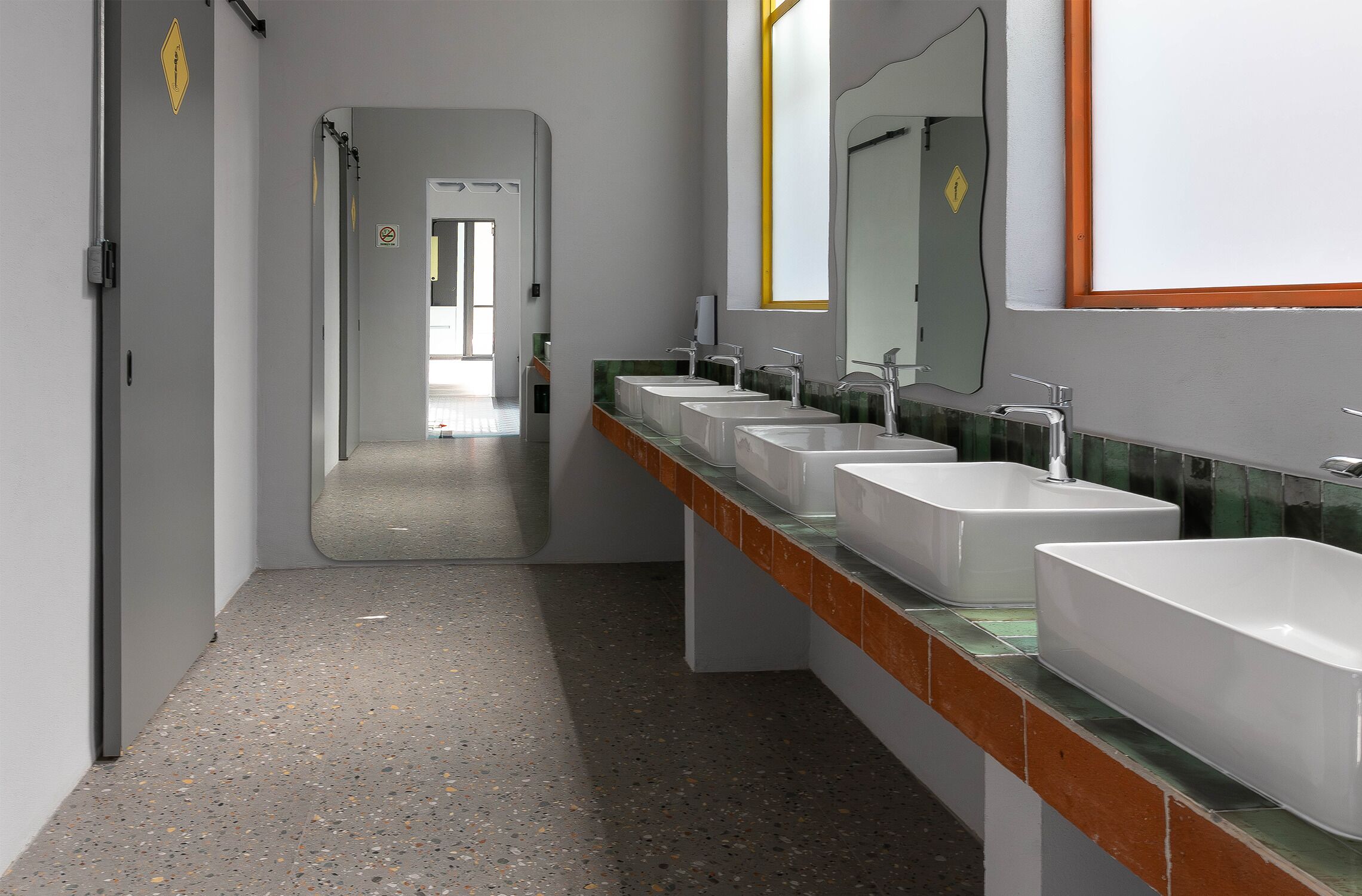 A modern bathroom with multiple sinks, a mirror, and a hallway leading to another room.
