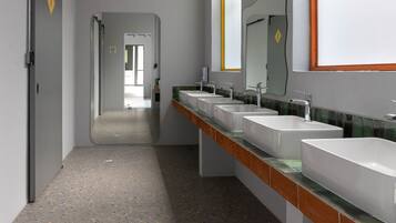 A modern bathroom with multiple sinks, a mirror, and a hallway leading to another room.