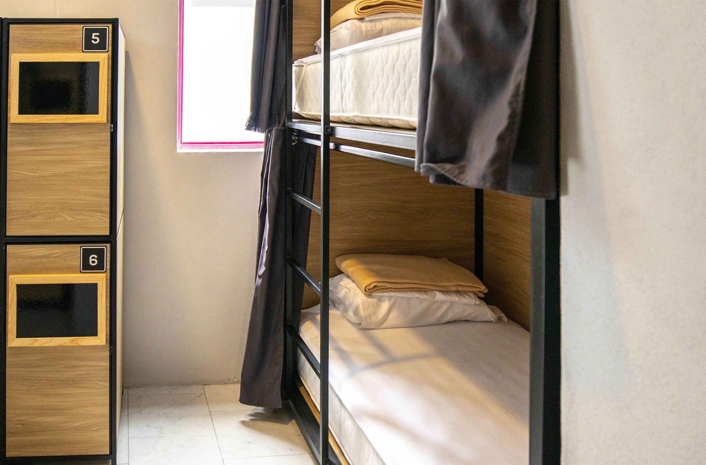 Habitación con literas, dos camas, colchones, almohadas y una cortina.