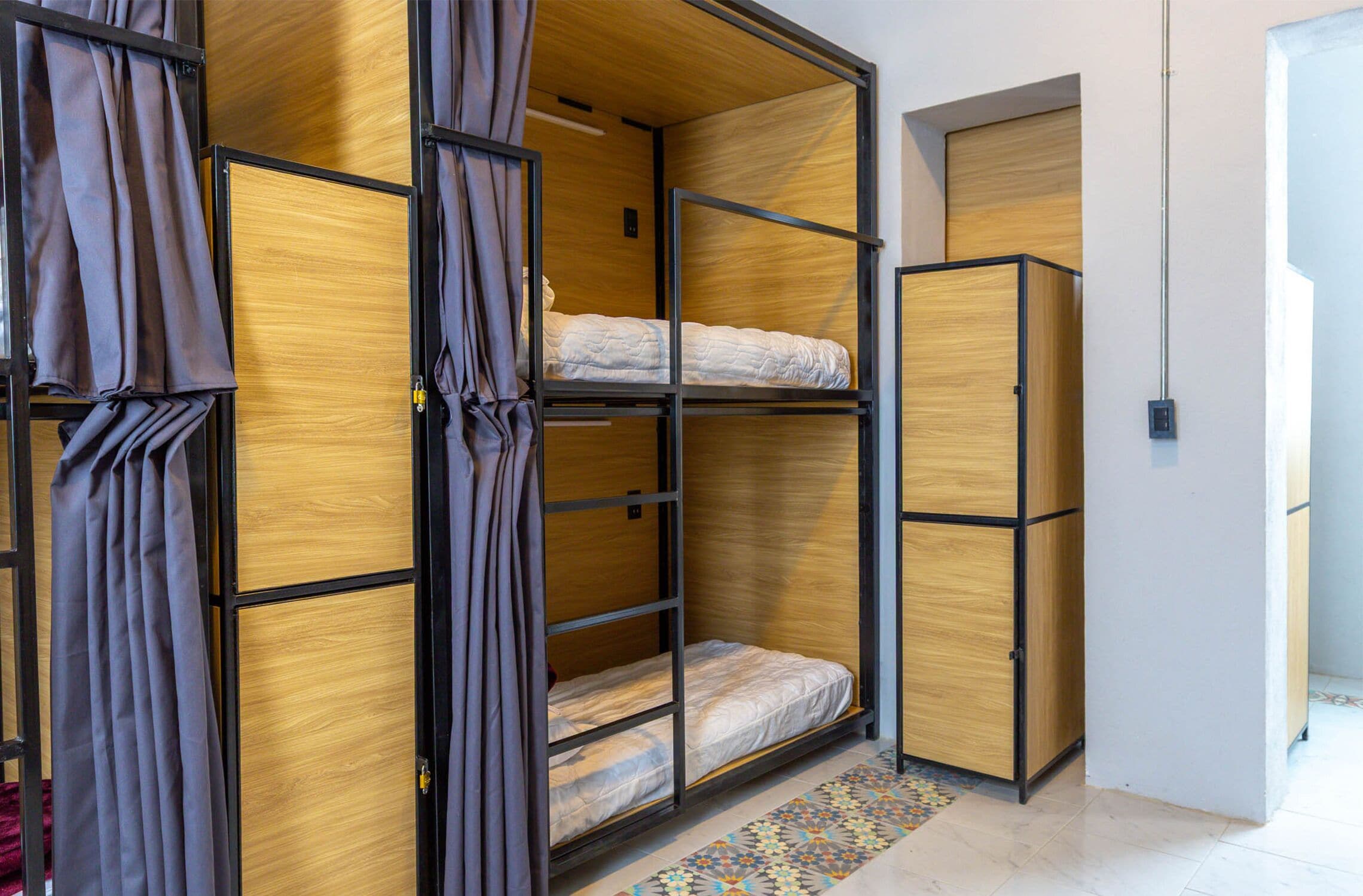 A room with a bunk bed, a wardrobe, and a curtain.