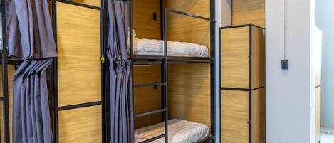 A room with a bunk bed, a wardrobe, and a curtain.
