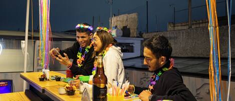 A group of people at a wooden table with a bottle and a yellow cup.