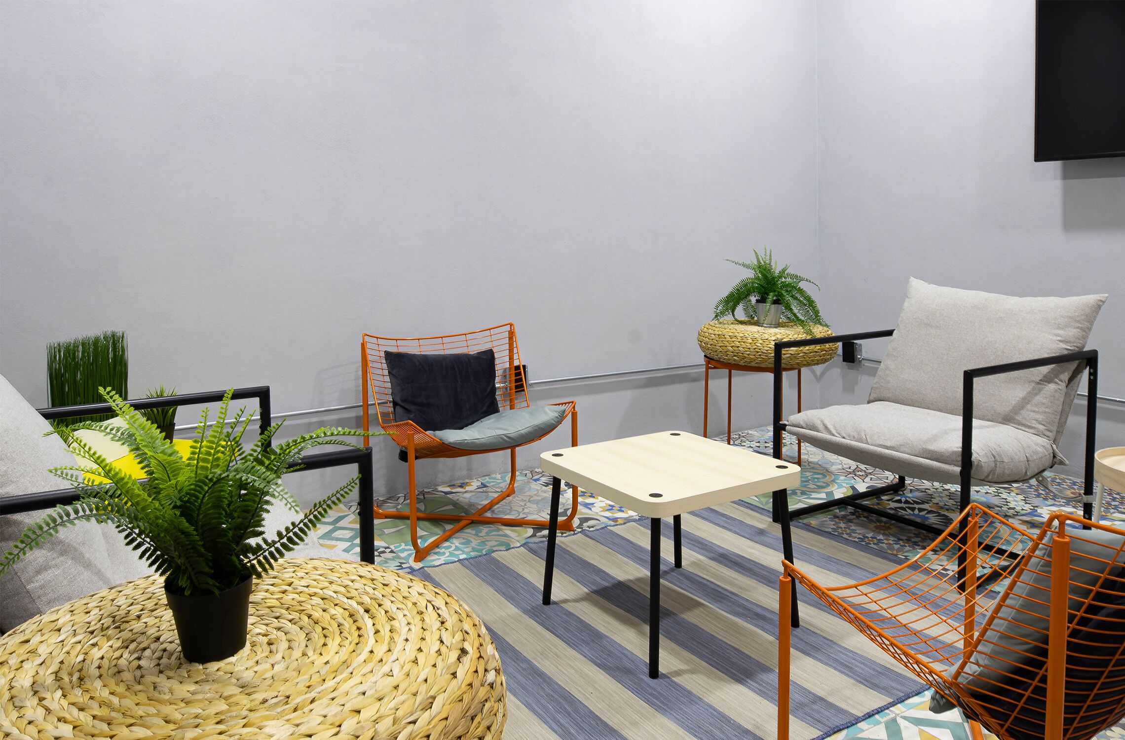 A modern living room with a sofa, armchair, small table, and decorative plants.