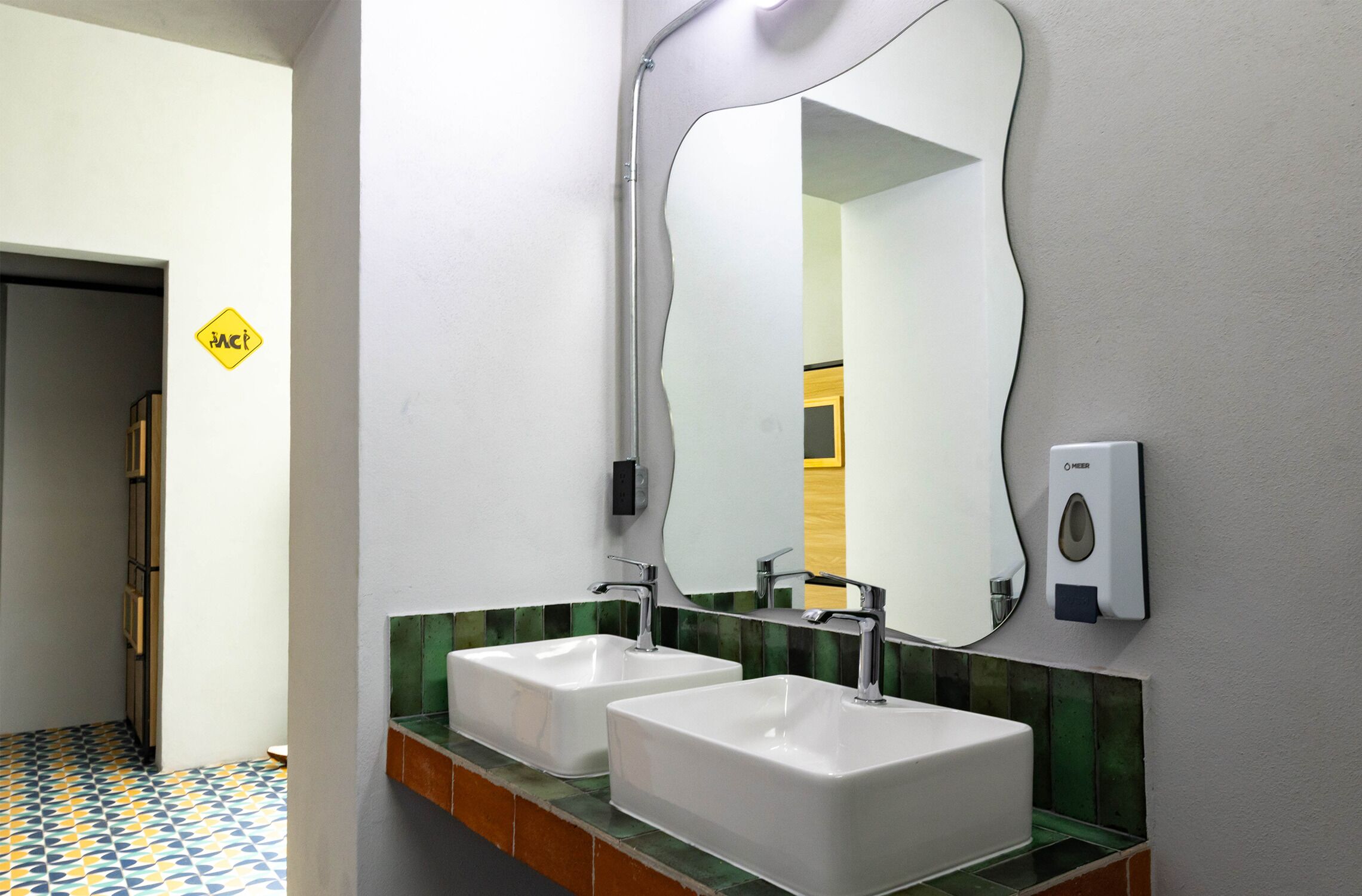Ein Badezimmer mit zwei Waschbecken, einem Spiegel und einem Händetrockner.
