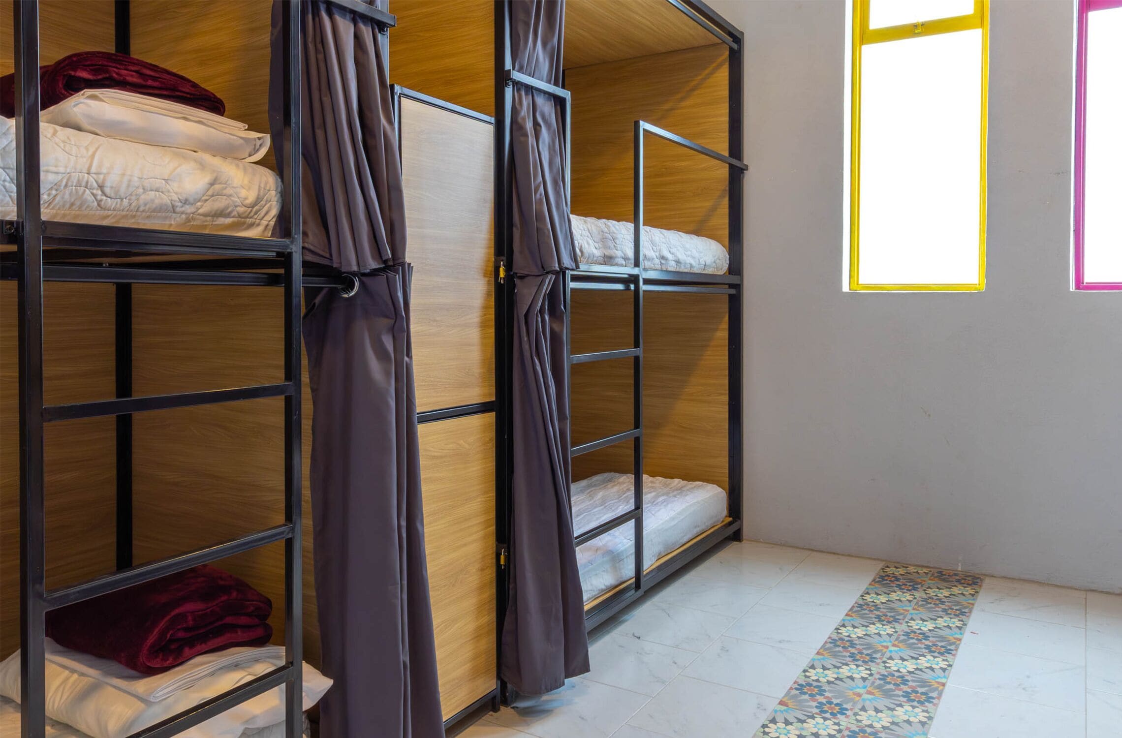 Una habitación con literas, paredes de madera y un suelo estampado.