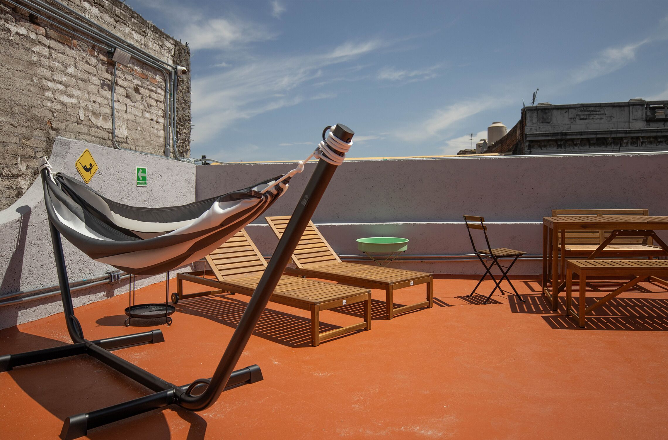 A rooftop terrace with a hammock, lounge chairs, and a table.