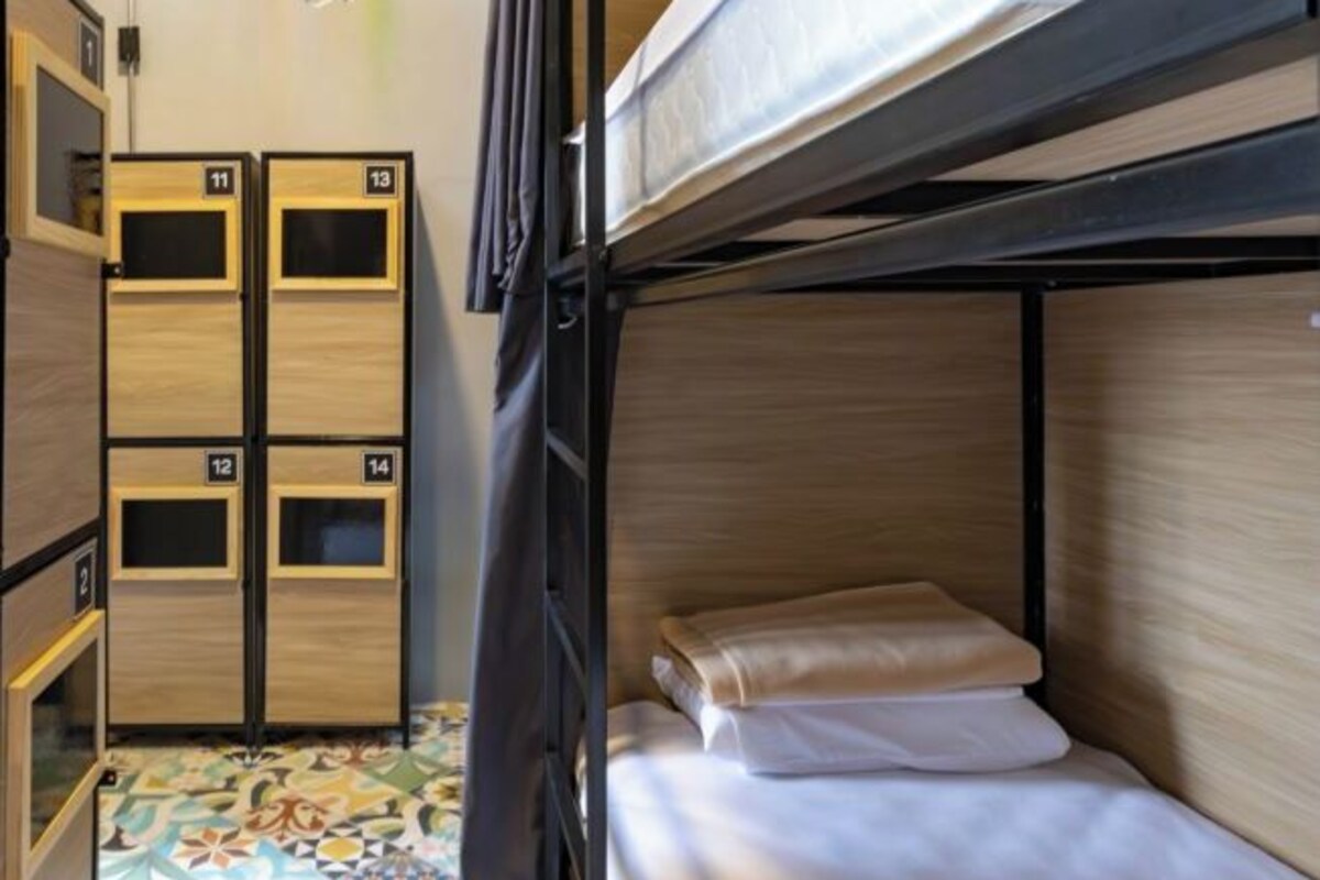 Een slaapkamer met een stapelbed, een patroon vloer en houten kasten met de nummers 11 tot en met 14.