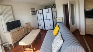 Ein Wohnzimmer mit Fernseher, Holzmöbeln, einer Couch mit Kissen und einer Raumteilerwand.