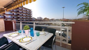 Un balcone con un tavolo apparecchiato per due persone, una pianta in vaso e vista su una zona residenziale.