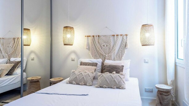 Un dormitorio con una cama grande, un colgador de macramé en la pared y lámparas de noche.