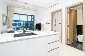 Une cuisine moderne dotée d’un îlot central, d’un coin repas avec un canapé et d’une grande fenêtre offrant une vue sur la ville.