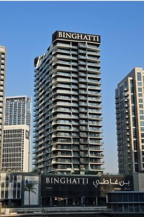 Un grand immeuble moderne, sur lequel le nom « BINGHATTI » est inscrit en lettres bien visibles sur la façade.