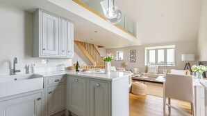 A modern kitchen with grey cabinets, a central island, and a staircase leading to an upper level. - Cobblestone Cottage - sleeps 4 guests  in 2 bedrooms (Docking)