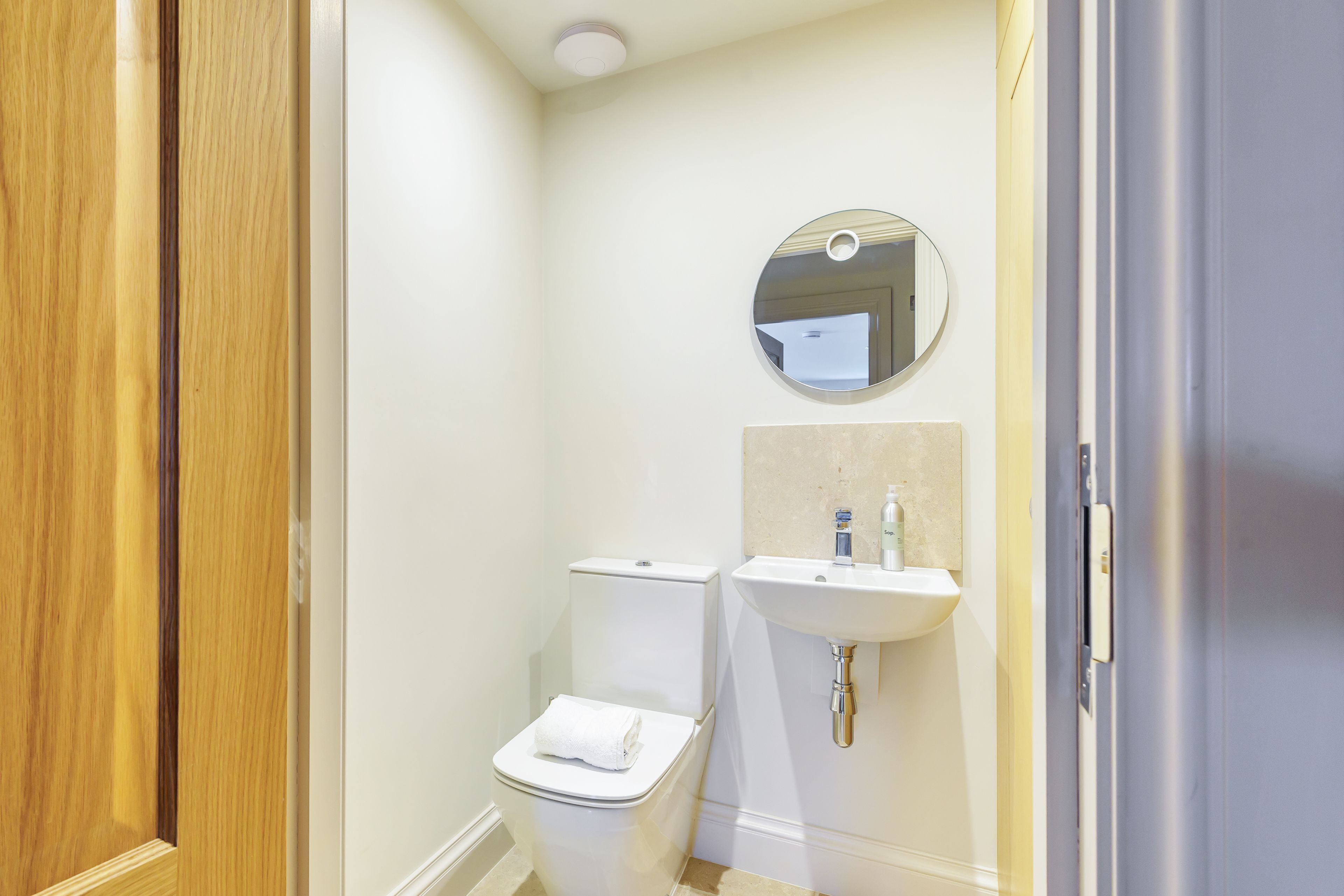 A small, clean bathroom with a toilet, sink, and mirror.