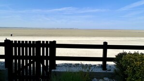 A wooden bench overlooking a beach with a clear sky. - 🏖️ Les Pieds dans le Sable - Unique Apartment with Direct Beach Access (Le Crotoy)