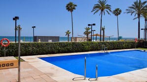 A swimming pool with a view of the ocean, palm trees, and a lifeguard stand. - Ref: 268 Stunning apartment on the beach front in Fuengirola with pool and parking (Fuengirola)