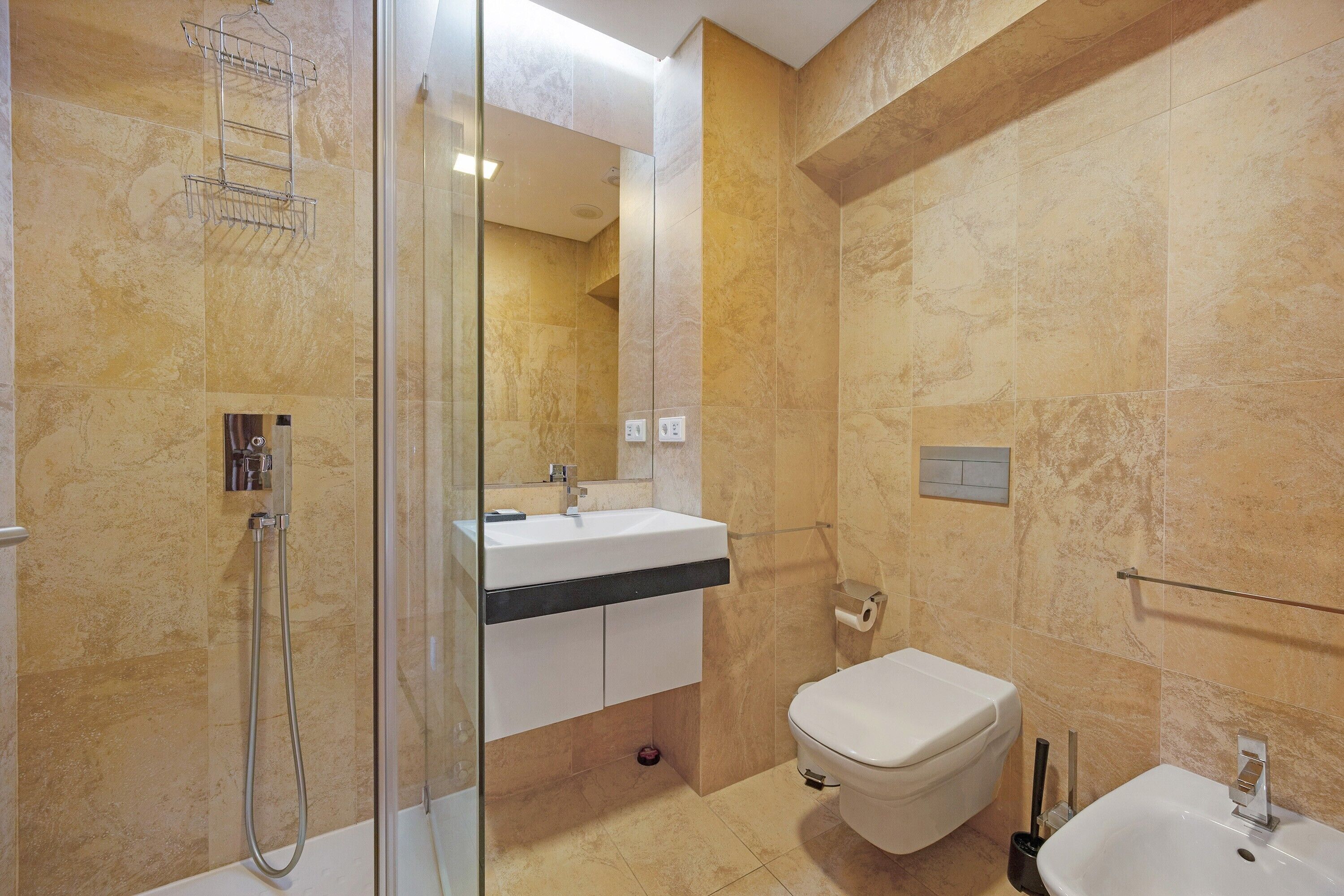 Un bagno con box doccia in vetro, un lavandino bianco e un water.