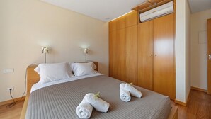 A hotel room with a large bed, wooden wardrobe, and bedside lamps. - Holiday Home 'Orange Lux Tavira Residence 3I' with Shared Pool, Wi-Fi and Air Conditioning (Luz de Tavira)