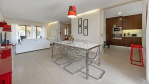A modern kitchen with a central island, stainless steel appliances, and a dining area with clear chairs. - Holiday Home 'Orange Lux Tavira Residence 3I' with Shared Pool, Wi-Fi and Air Conditioning (Luz de Tavira)
