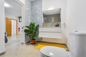 Et moderne badeværelse med toilet, håndvask og spejl.