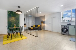 A modern living space with a dining area, sofa, laundry area, and a view of the sky. - Vacation 'Tea-Rose Loft' with Shared Garden, Wi-Fi and Air Conditioning (Conil Tías)