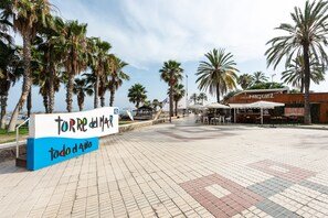 Un camino pavimentado con palmeras, un letrero que dice 'TORRE del MAR todo el año', y un edificio con el rótulo 'CASA MICUEL'.