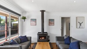 A living room with a wood-burning stove, grey sofas, a wooden coffee table, and framed artwork on the walls.