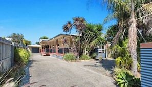 A residential property with a covered porch, a garage, and a variety of tropical plants.