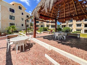 A covered outdoor area with a thatched roof, white plastic chairs, and a tiled floor. - Ocean View PH in Punta Sur (Isla Mujeres)