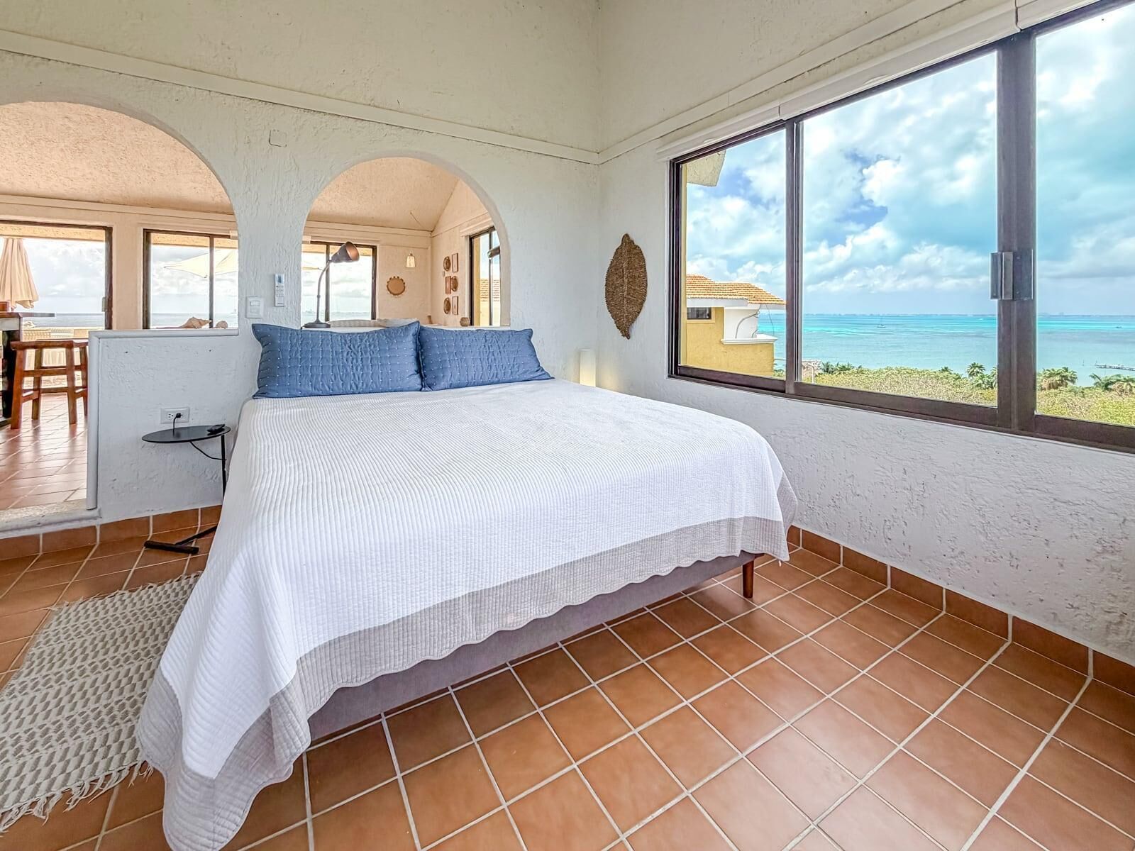 Un dormitorio con una cama grande, vistas al océano y una zona de comedor con mesa y sillas.