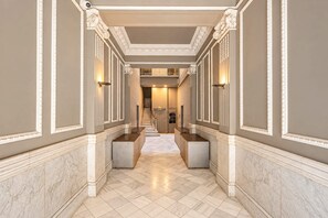 A hallway with marble flooring, white wall moldings, and a staircase leading to an upper level.