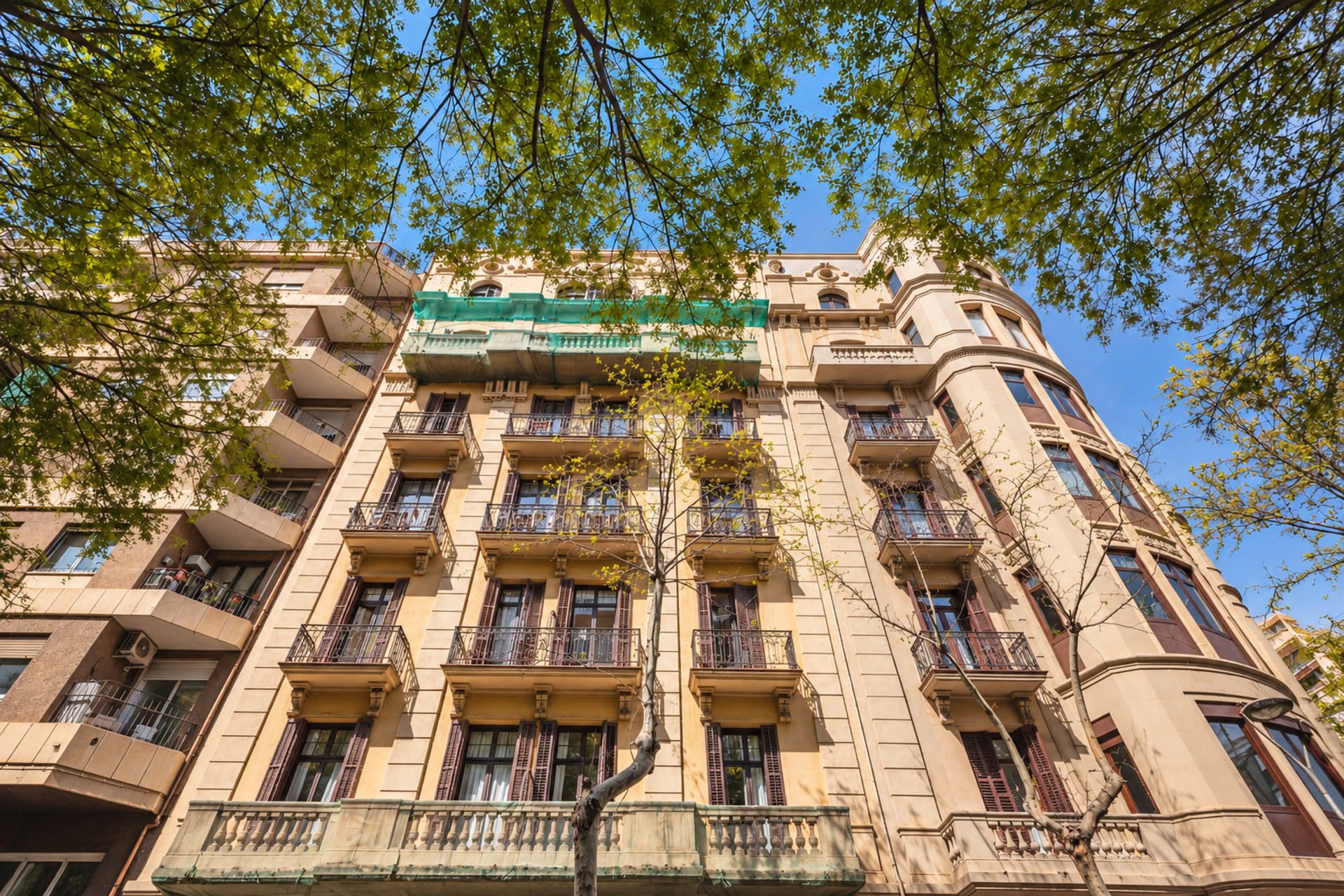 A multi-story building with balconies, a green awning, and a clear blue sky.