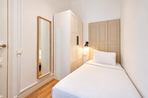 Une chambre d’hôtel équipée d’un lit, d’une armoire, d’un miroir et d’une lampe fixée au mur.